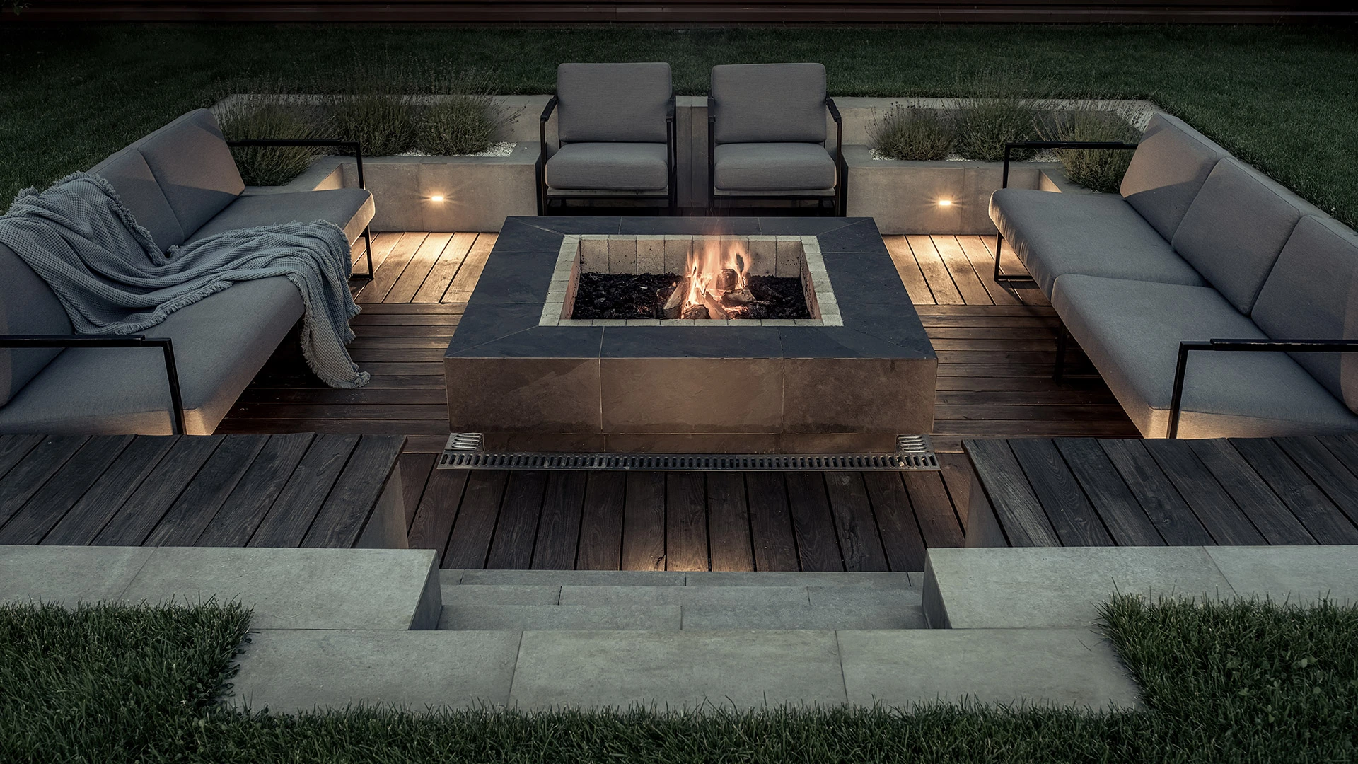 A custom rectangular fire pit surrounded by couches and chairs behind a home in Coopersburg, PA. 