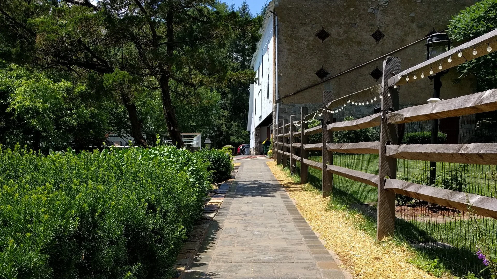 Stone walkway between a wooden fence and lush green shrubs in Hanover, PA.