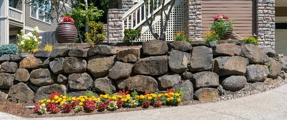 Boulder retaining wall in Macungie, PA, and colorful flowers.