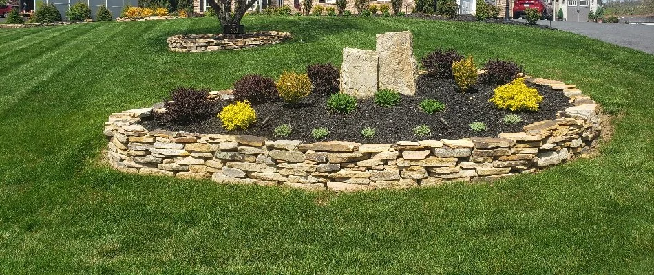 Natural stacked stone retaining wall around a landscape bed in Macungie, PA.