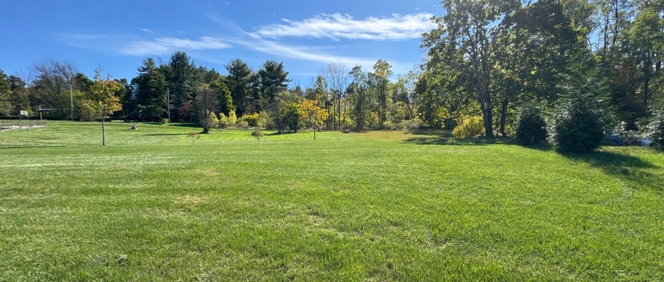 Lawn care worker applying granular fertilizer to a lawn near Emmaus, PA